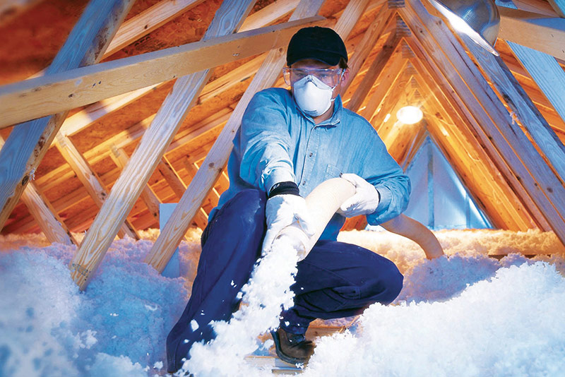 Technicien du bâtiment certifié Qualibat et RGE pendant l'isolation des combles d'une maison